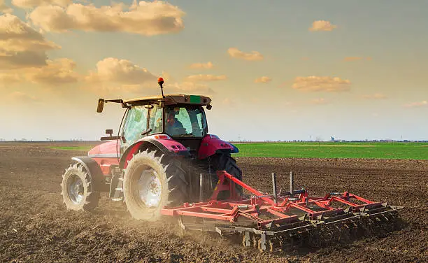 Photo of Farmer in tractor preparing land with seedbed cultivator