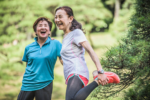 Two active Japanese women laughing, one stretching leg