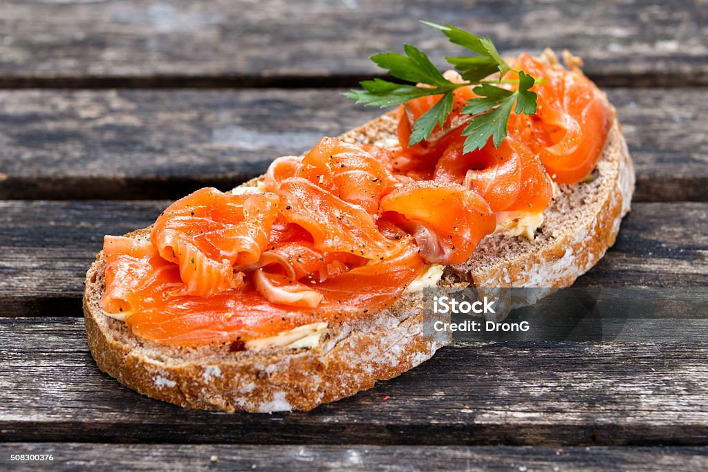 Fresh homemade sandwich with salmon on old wooden table Fresh homemade sandwich with salmon on old wooden table. Crostini Stock Photo
