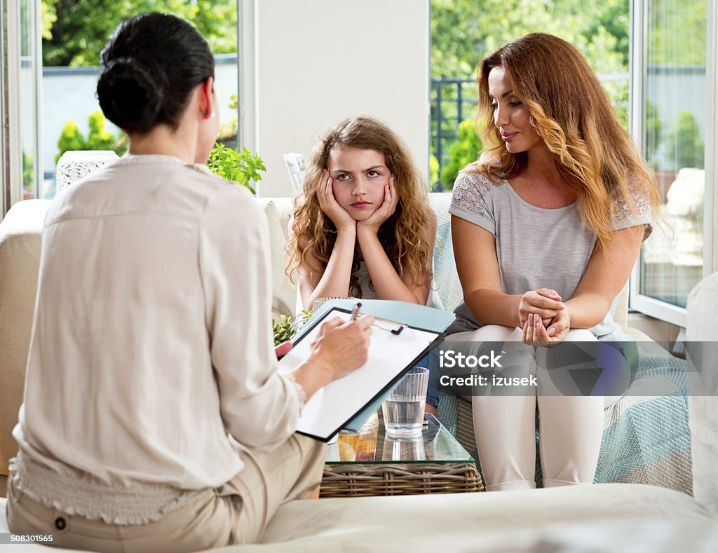 Meeting with therapist Mother and her teenager daughter talking with therapist at home. Child Stock Photo