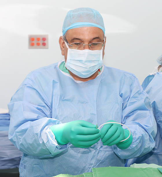 Doctor preparing a catheter for insertion Doctor preparing a catheter for insertion on a patient. Slide Safe-T-J wire guide straightener. chemical straightener stock pictures, royalty-free photos & images