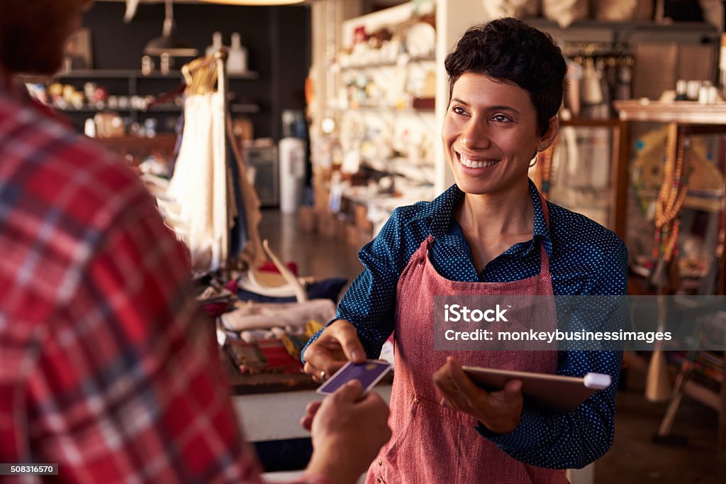 Sales Assistant With Credit Card Reader On Digital Tablet Small Business Stock Photo