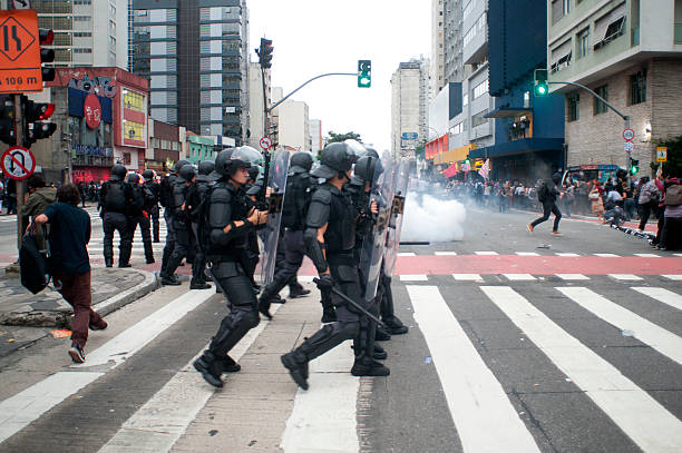 Riot Police São Paulo, Brazil, January, 12, 2016: Police officer in riot gear fire tear gas bombs during act on Paulista Avenue against the increase in tariffs in urban transport police tear gas stock pictures, royalty-free photos & images