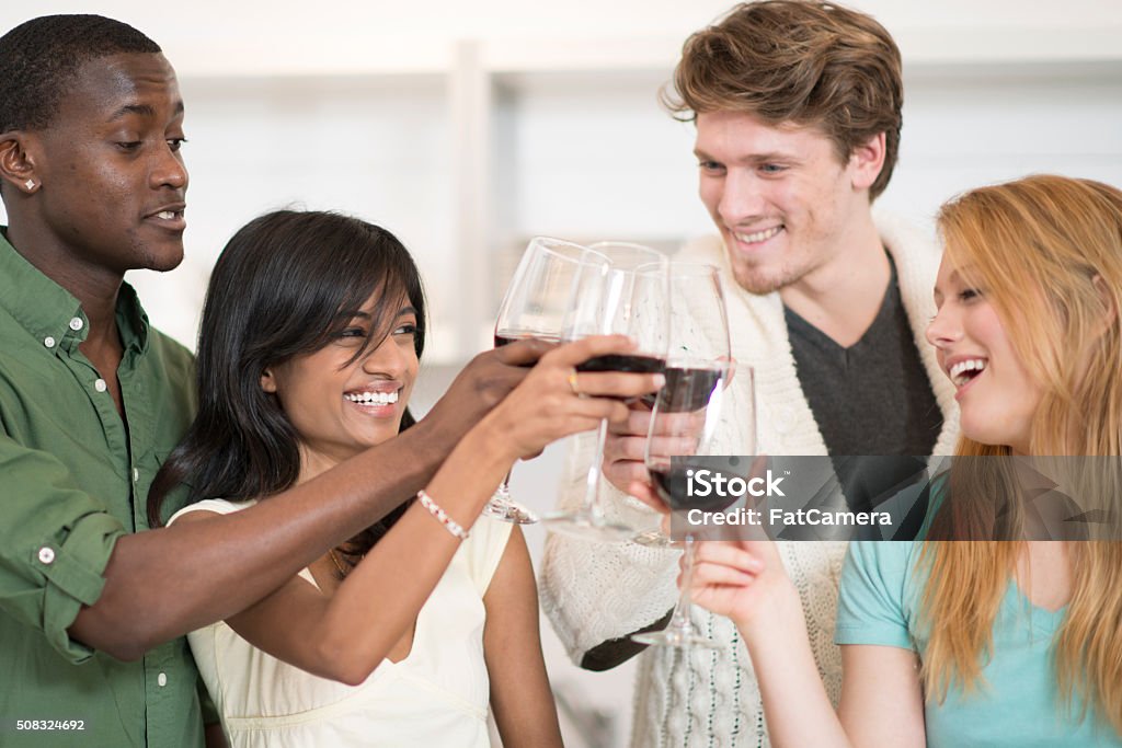 Friends Enjoying Wine A multi-ethnic group of young adults are relaxing together and are drinking a glass of wine. Celebratory Toast Stock Photo