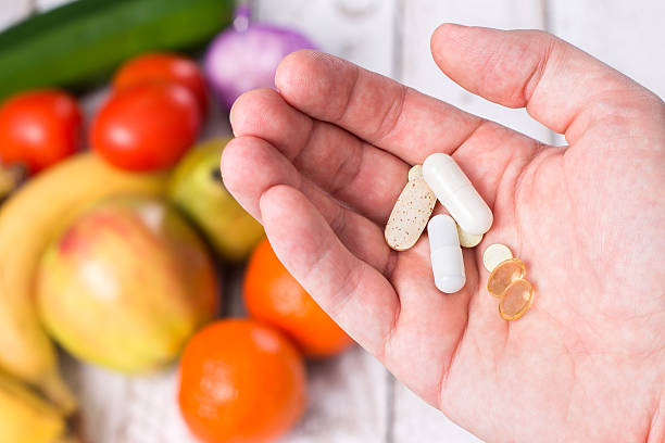 istock Hand with dietary supplements on fruity background 508326350