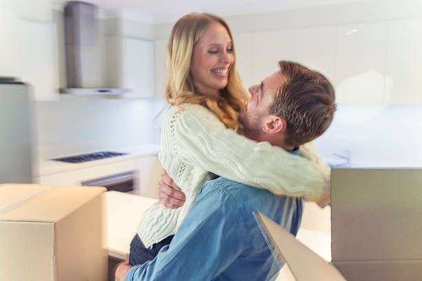 jeune couple debout dans la nouvelle maison avec des boîtes de rangement. - apartment contemporary action packing photos et images de collection