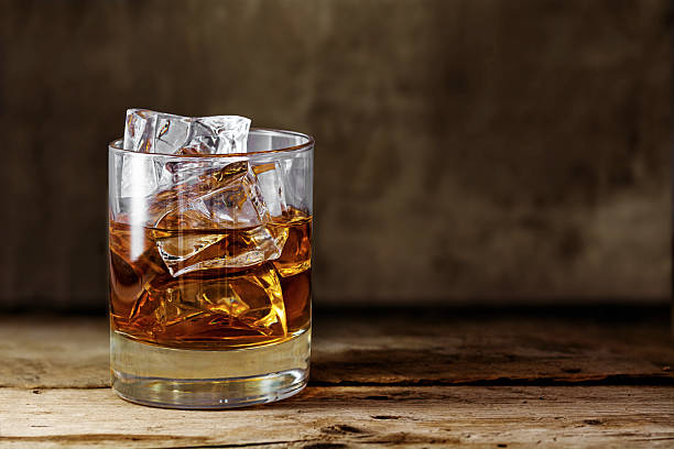 glass scotch whiskey with ice on a rustic wooden table stock photo