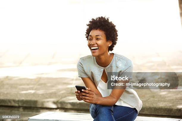 Beautiful Young African Woman Smiling Outside With Mobile Phone Stock Photo - Download Image Now