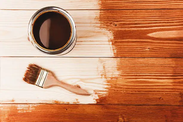 Varnishing a wooden shelf. Paintbrush and can on the wooden surface