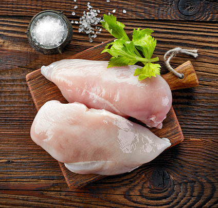 raw chicken fillets on wooden cutting board, top view