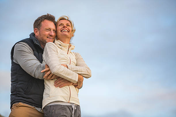 feliz abrazando medio de activa en forma saludable de pareja en la playa al aire libre - couple mature adult action walking fotografías e imágenes de stock