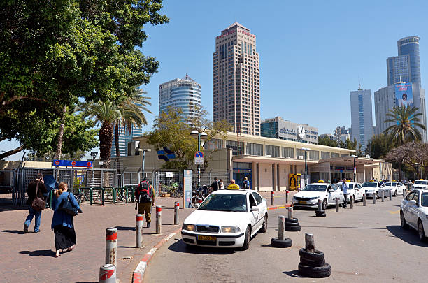 Tel Aviv, Israel - March 26, 2015: Taxis wait on the side of the road and padestrians walk to Tel Aviv Savidor Central Railway Station. It's the busiest train station in Israel serves most rail lines on 6 passenger platform with a daily average of 70,073 passengers.