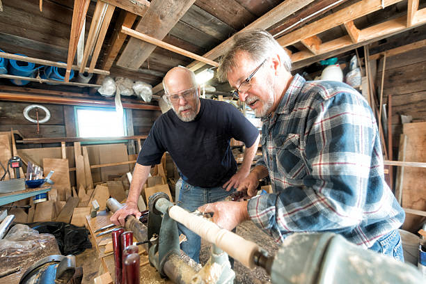 Instructor demonstrating wood turning on a lathe a  to senior man stock photo