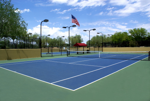 Blue tennis court with the American flag in the background