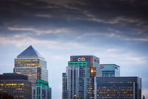 London, United Kingdom - August 20, 2014: The London Canary Wharf skyline viewed from Greenwich near the Cutty Sark, showing the illuminated signs on the buildings.