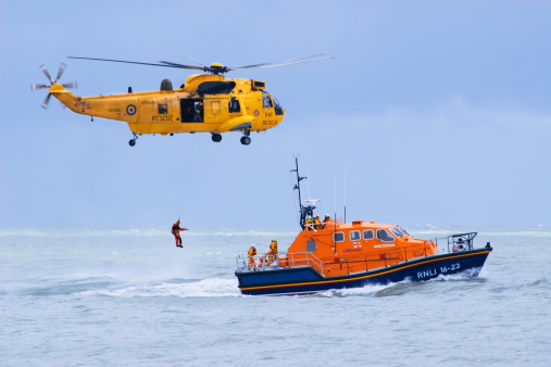 Eastbourne, United Kingdom - August 17, 2014: RAF Rescue helicopter and RNLI rescue boat demonstrating their skills during the Eastbourne AirShow.