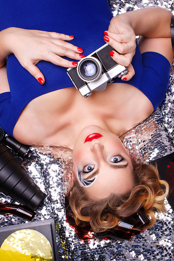 Young girl photographer with a creative make-up and hairstyle. The hairstyle film. Face art in the form of aperture camera. Girl is holding a retro camera.