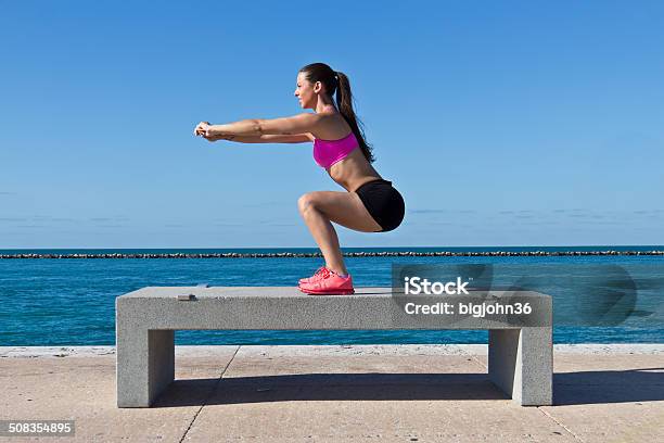 Hispanic Woman Doing Squats By The Water Stock Photo - Download Image Now - Adult, Adults Only, Athlete