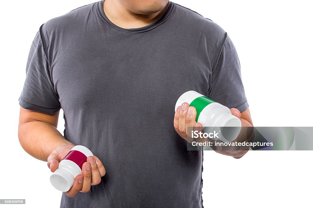 Man Comparing Brands of Dietary Supplements Male comparing bottles of medicine or dietary supplements.  He is holding two pill bottles for comparison.  The bottles have copyspace for logos.  The image can also be depicting a comparison between medicine and generic drugs. Advertisement Stock Photo