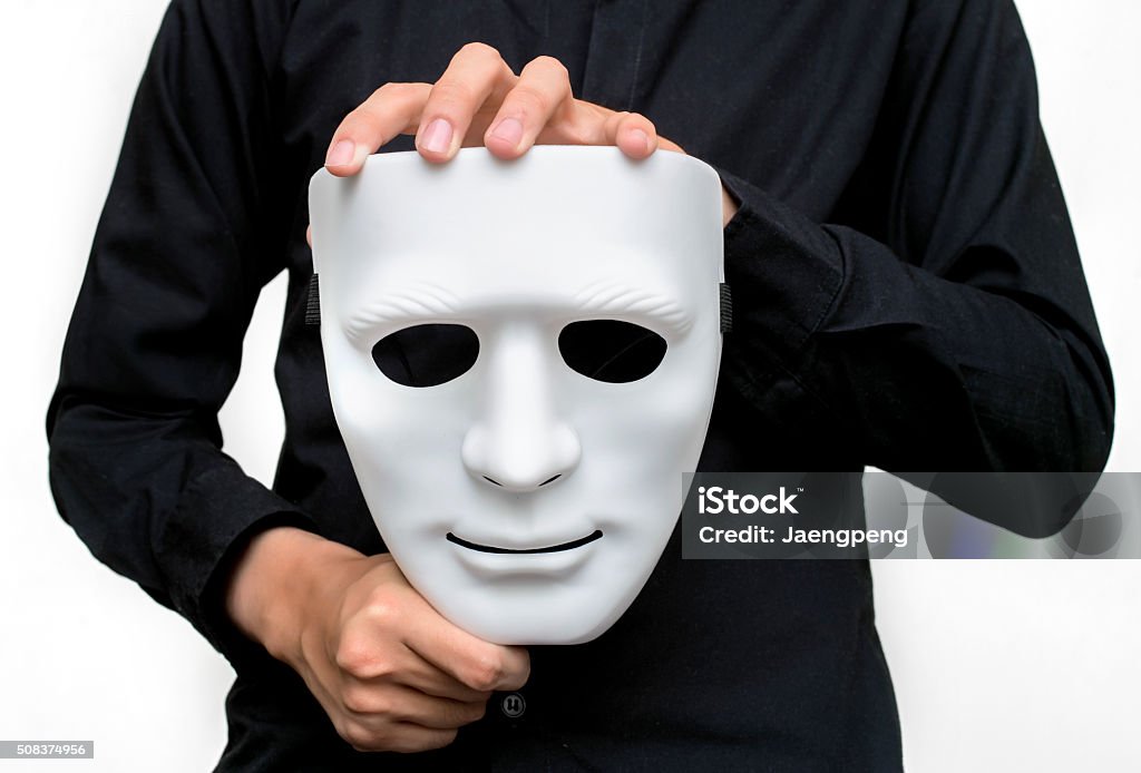 Man wearing black shirt holding a white mask Man wearing black shirt holding a white mask with white background. Acting - Performance Stock Photo