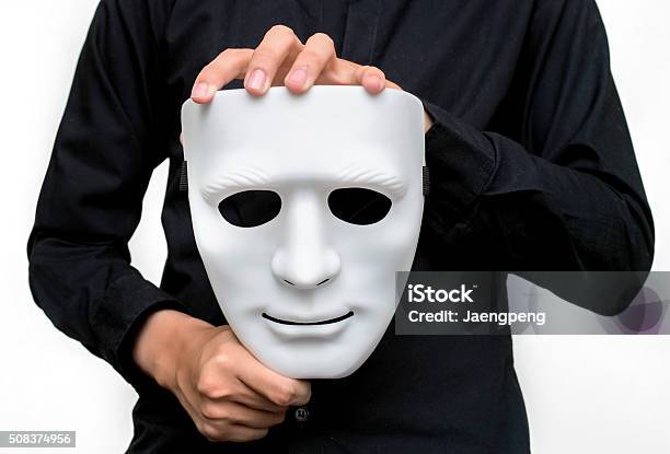 Man Wearing Black Shirt Holding A White Mask Stock Photo - Download Image Now - Acting - Performance, Adult, Black Color