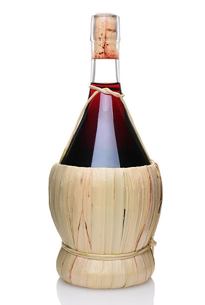 Bottle of Chianti Wine A single bottle of Chianti wine with a wicker basket base. Vertical format isolated on white with reflection. chianti region stock pictures, royalty-free photos & images