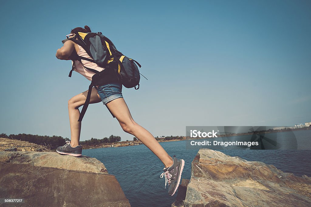 Climbing Female tourist with backpack climbing a rock Active Lifestyle Stock Photo