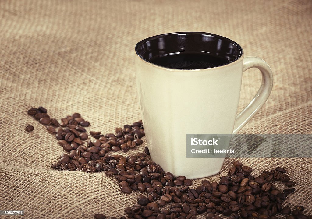 Cup of coffee and beans Cup of black coffee and coffee beans on burlap background, shallow depth of field, vintage filter effects Backgrounds Stock Photo