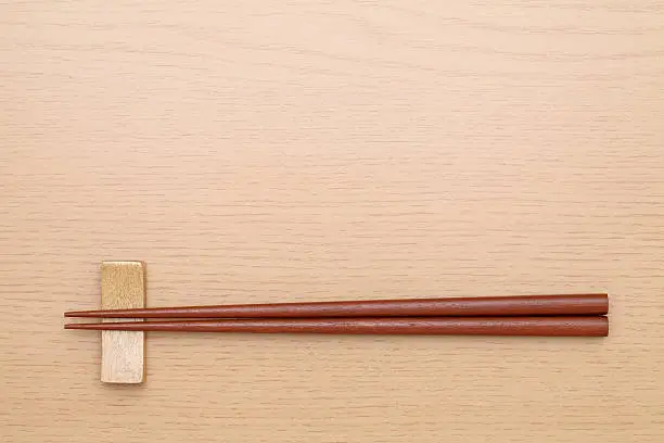 Chopsticks and chopsticks rest on wooden table   