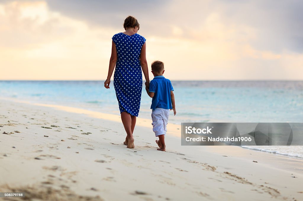 mother and son walking on sunset beach mother and little son walking on sunset beach Beach Stock Photo