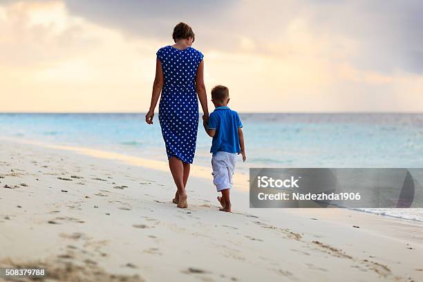 Mother And Son Walking On Sunset Beach Stock Photo - Download Image Now - Beach, Mother, Adult