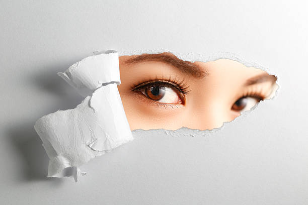 istock woman looking through torn paper 508380928