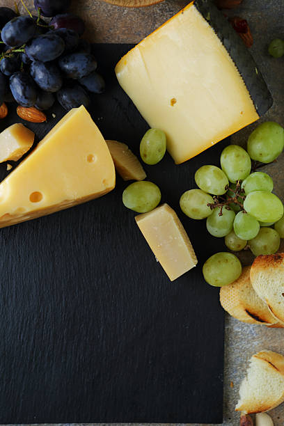 istock yellow cheese with grapes on slate background 508382328