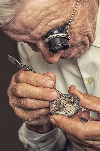 old watchmaker repairing clocks