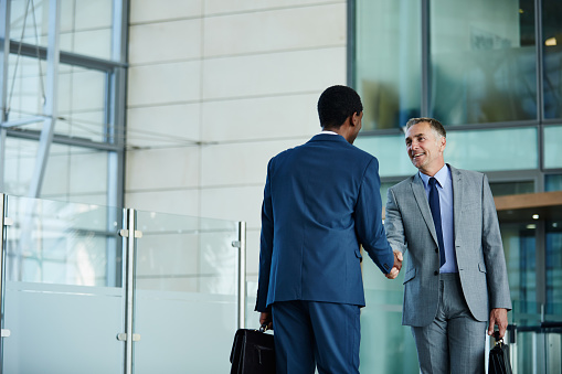 Shot of two businessmen shaking hands in the lobby of an office building