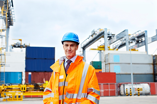 Portrait of a mature man in workwear standing outside on a large commercial dock
