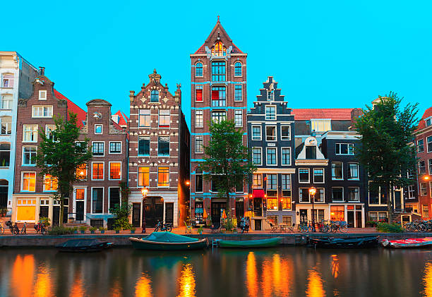 Night Amsterdam canals and typical houses, Holland, Netherlands Night city view of Amsterdam canals and typical houses, boats and bicycles, Holland, Netherlands. canal house stock pictures, royalty-free photos & images