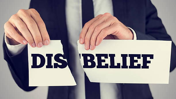 Man holding torn paper with the words Dis-Belief Man holding a torn paper sign in his hands with the words - Dis - Belief - spread over the two halves depicting the concept of opposites - Belief and Disbelief. disempower stock pictures, royalty-free photos & images