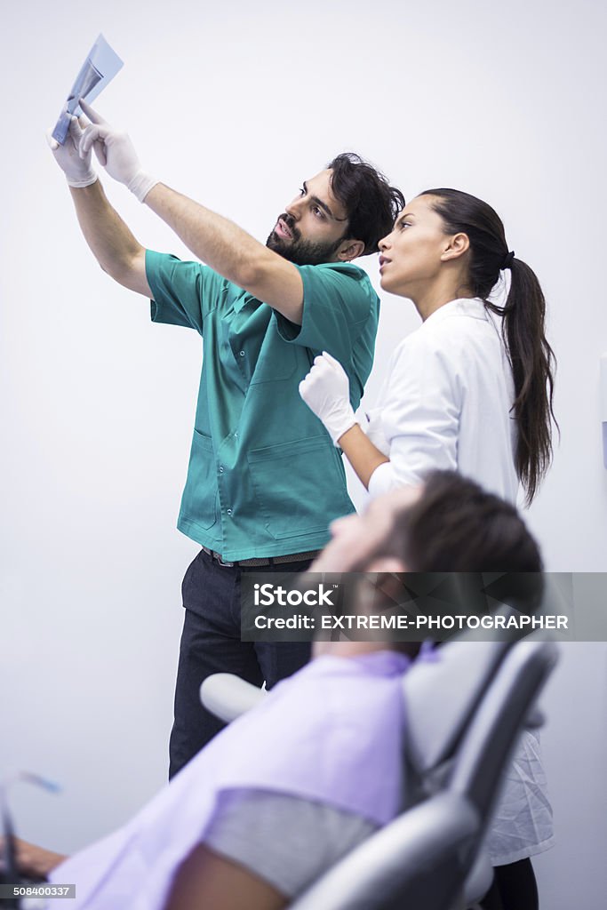 Dental x-ray image Dentist and technician looking at x-ray image. Patient sitting in the chair. Adult Stock Photo