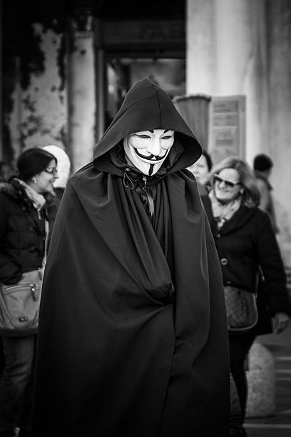 Man wears a V for vendetta, Guy Fawkes mask Venice, Italy - February 4, 2016: Man wears a V for Vendetta (Guy Fawkes) mask whilst attending the 2016 Venice Carnival, Italy black and white portrait photographers stock pictures, royalty-free photos & images