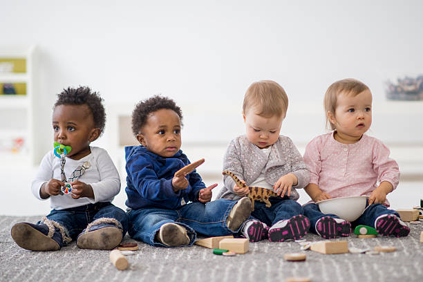 Group of Toddlers Playing Together A multi-ethnic group of toddlers are sitting on the floor and are playing together with toys while on a play date. group of babies stock pictures, royalty-free photos & images