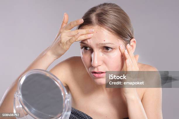 Young Woman Squeeze Her Acne In Front Of The Mirror Stock Photo - Download Image Now