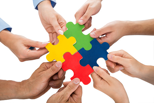 Close-up Of People Hands Connecting Together Jigsaw Pieces