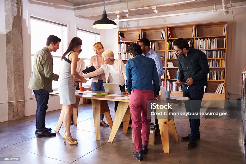 Business Team Meeting Around Table For Brainstorming Session Standing Stock Photo