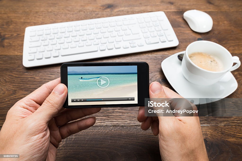 Person Watching Video On Mobile Phone Close-up Of Person Watching Video On Mobile Phone With Cup Of Tea At Desk Movie Stock Photo