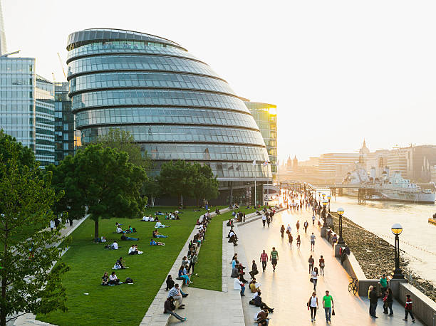 London Riverbank Tourists  and locals walking on the riverbank of Thames. City hall on the left. southwark stock pictures, royalty-free photos & images