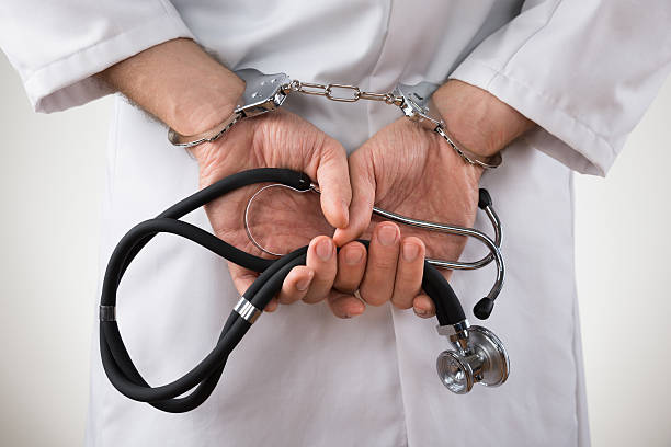 Doctor Hands In Handcuffs Close-up Of Doctor Hands With Stethoscope In Handcuffs white collar crime handcuffs stock pictures, royalty-free photos & images