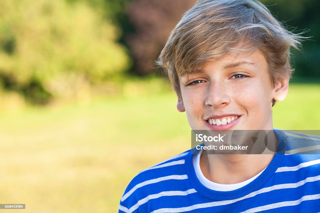 Happy Boy Male Child Teenager Smiling Young happy smiling male boy teenager blond child outside in summer sunshine wearing a blue sweatshirt Teenage Boys Stock Photo