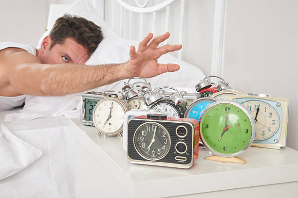 Man shutting off alarm clocks Man shutting off alarm clocks alarm clock snooze stock pictures, royalty-free photos & images