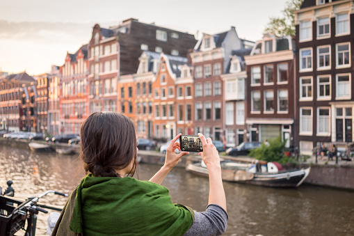 beautiful young woman takes pictures in vacation spent in Amsterdam with beautiful architecture